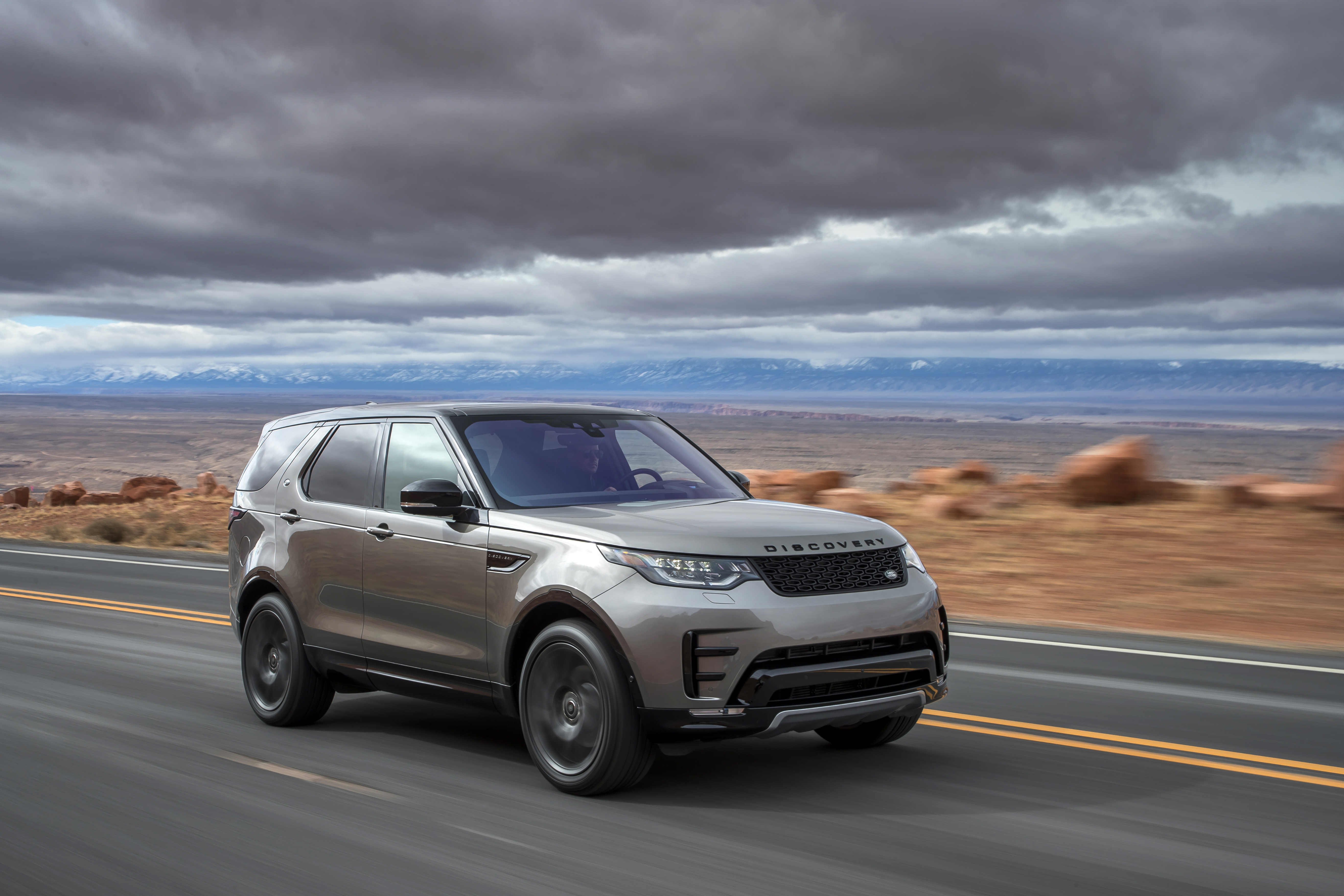 Pale gold Land Rover Discovery driving at speed side on to you